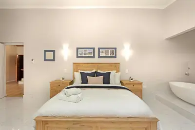 a bedroom with a bed and a tub and a sink at Zaria Sun Penthouse in Cape Town