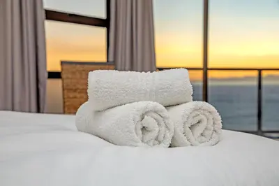 a pile of towels sitting on a bed with a window at Zaria Sun Penthouse in Cape Town
