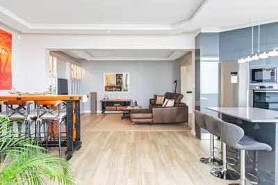 a kitchen and living room with a table and chairs at Zaria Sun Family in Cape Town