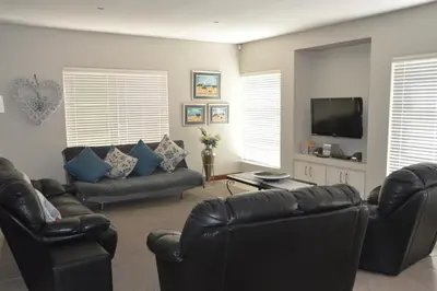 a living room with leather furniture and a flat screen tv at Piece of Paradise in Hermanus