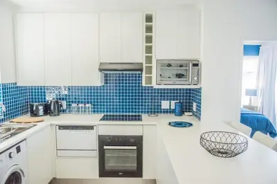 a kitchen with white cabinets and blue tiles at Whale Rock 40 in Hermanus