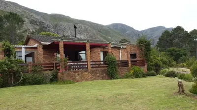 a small brick house with mountains in the background at Lagoon Edge in Hermanus