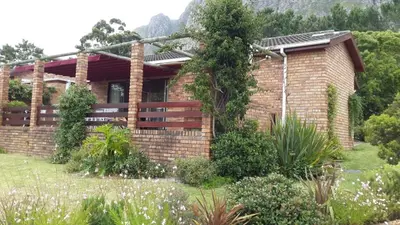 a brick house with a fence in a garden at Lagoon Edge in Hermanus