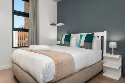 a bedroom with a large white bed with a window at Matrix Apartments in Cape Town
