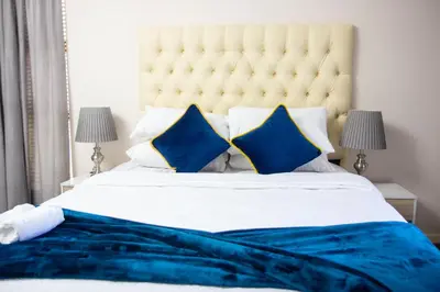 a bedroom with a large bed with blue sheets and pillows at Wilcre's blouberg home in Cape Town