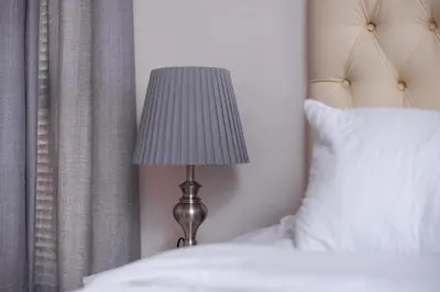 a lamp sitting next to a bed with white pillows at Wilcre's blouberg home in Cape Town