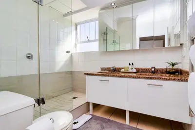 a bathroom with a shower and a toilet and a sink at Hermanus Beachfront Lodge - Solar Power in Hermanus