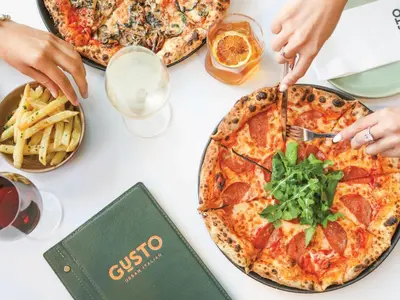 a table with three pizzas and french fries at Bridgewater Apartments by Century City Hotels in Cape Town