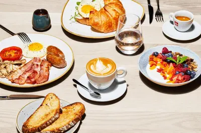 a table with plates of breakfast food and a cup of coffee at Bridgewater Apartments by Century City Hotels in Cape Town
