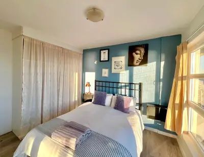 a bedroom with blue walls and a bed with purple pillows at Ocean View Apartment in Cape Town