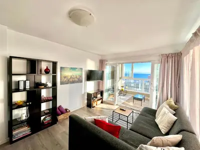a living room with a couch and a large window at Ocean View Apartment in Cape Town