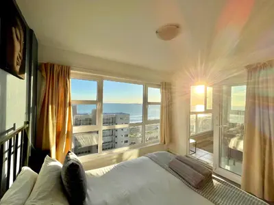 a bedroom with a bed and a large window at Ocean View Apartment in Cape Town