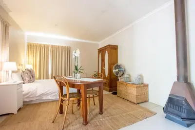 a bedroom with a table and a bed and a fireplace at Hoogwater Cottage in Wolseley