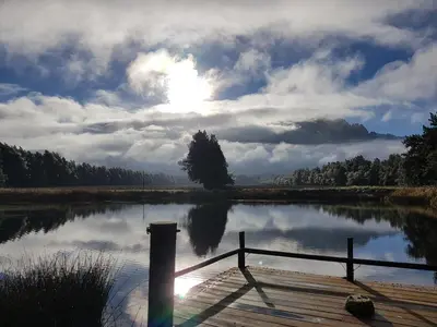 a view of a lake with the sun reflecting on the water at Hoogwater Cottage in Wolseley