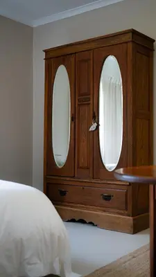 a wooden dresser with two mirrors in a bedroom at Hoogwater Cottage in Wolseley