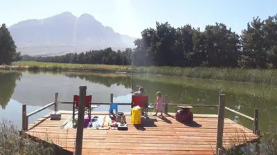 a man and a child sitting on a dock on a lake at Hoogwater Family House in Wolseley