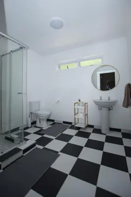 a bathroom with a glass shower and a checkered floor at Hoogwater Family House in Wolseley