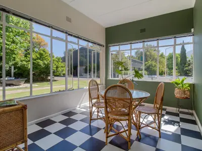 a dining room with a table and chairs and windows at Hoogwater Family House in Wolseley