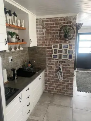 a kitchen with a brick wall and a sink at Just Chill Betty's Bay in Bettyʼs Bay