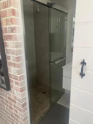 a glass shower in a bathroom next to a brick wall at Just Chill Betty's Bay in Bettyʼs Bay