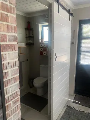 a bathroom with a toilet and a brick wall at Just Chill Betty's Bay in Bettyʼs Bay