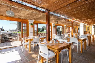 a restaurant with wooden tables and white chairs at Harbour House Hotel - Manor House in Hermanus