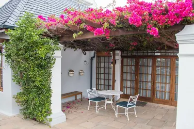a patio with a table and chairs and flowers at Harbour House Hotel - Manor House in Hermanus