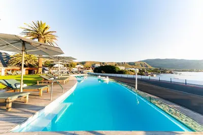 a swimming pool with chairs and a view of the water at Harbour House Hotel - Manor House in Hermanus