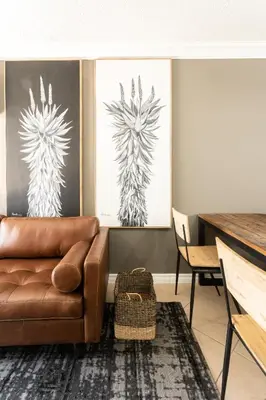 a living room with a brown couch and two paintings at Avemore Jan Cats No 3 full back up power in Stellenbosch