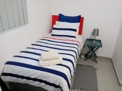 a bedroom with a bed with blue and white stripes at Covenant Place in Cape Town