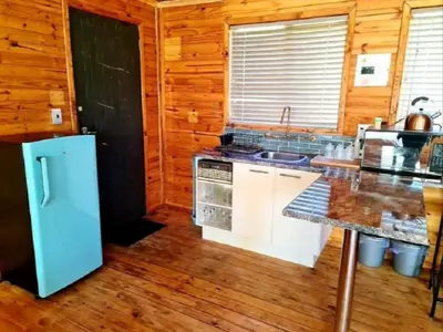 a kitchen with a refrigerator and a counter top at Hoogeland's Wood Cabins in Eersterivier