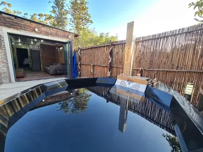 a pool of water in a yard with a wooden fence at Hoogeland's Wood Cabins in Eersterivier