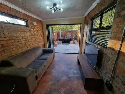 a living room with a couch and a brick wall at Hoogeland's Wood Cabins in Eersterivier