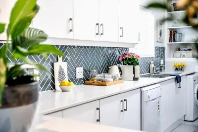 a kitchen with white cabinets and flowers on the counter at Milas Place Spacious & Comfortable at Bayview in Hermanus