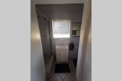 a bathroom with a white toilet and a window at Cozy, peaceful garden cottage in Cape Town