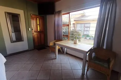 a dining room with a table and chairs and a window at Cozy, peaceful garden cottage in Cape Town