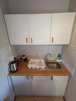a small kitchen with a sink and white cabinets at Cozy, peaceful garden cottage in Cape Town