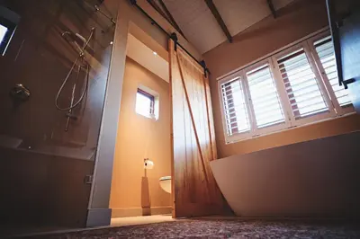 a bathroom with a toilet and a window and a door at The Cottage Farm in Stellenbosch