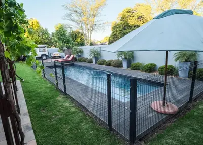 a fence with an umbrella next to a swimming pool at The Cottage Farm in Stellenbosch