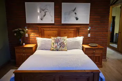 a bedroom with a bed and two pictures of horses on the wall at The Cottage Farm in Stellenbosch