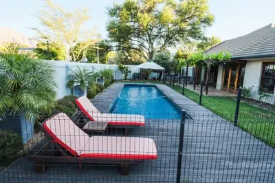 a swimming pool with two red chairs and a pool at Home in Cape Town-The Homestead in Stellenbosch