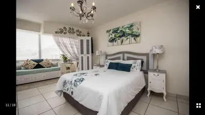 a bedroom with a bed and a window and a couch at Strand Getaways Apartment in Cape Town