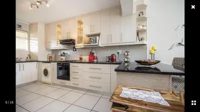 a kitchen with white cabinets and a black counter top at Strand Getaways Apartment in Cape Town