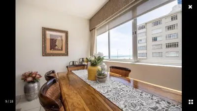 a dining room with a table and a large window at Strand Getaways Apartment in Cape Town
