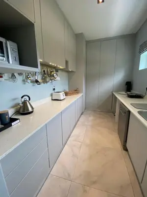 a kitchen with white cabinets and a tile floor at Beach & Mountain Retreat within a UNESCO Biosphere in Rooiels