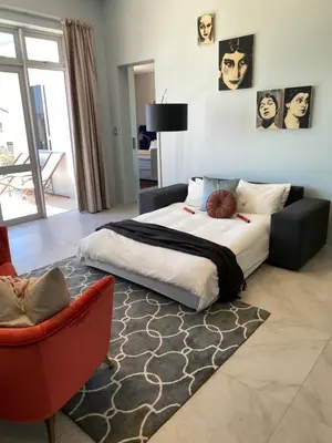 a bedroom with a large bed and a red chair at Beach & Mountain Retreat within a UNESCO Biosphere in Rooiels