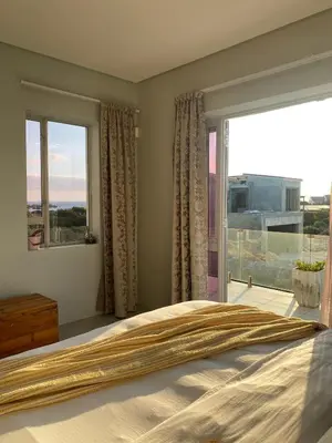a bedroom with a bed and a large window at Beach & Mountain Retreat within a UNESCO Biosphere in Rooiels