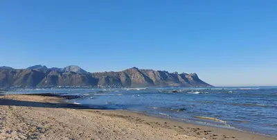 a beach with rocks in the water and the ocean at Tranquil Impulse on Strand in Cape Town