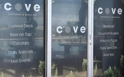 a glass door with a sign for a restaurant at Tranquil Impulse on Strand in Cape Town