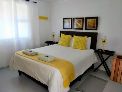 a bedroom with a large bed with yellow pillows at Cottage Amnesia in Bettyʼs Bay